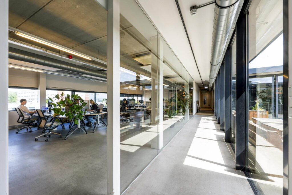 Modern office space at Johan van Hasseltweg with glass walls, open workstations, and natural light from large windows.